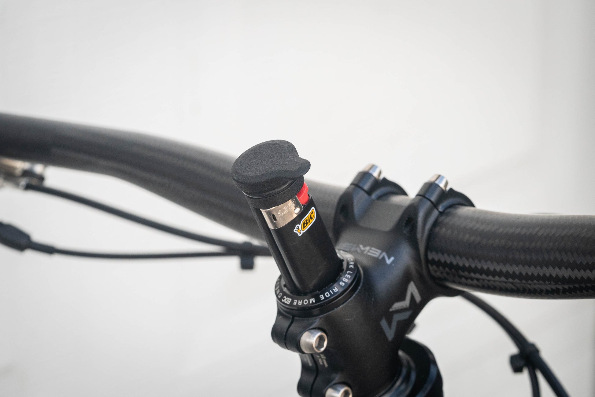Image: The Climb Switch High Performance System, a discreet and practical bike accessory, discreetly stores a custom machined one-hitter, a Mini BIC lighter, and a small amount of material inside your bike's steerer tube. Designed to seamlessly integrate with the OneUp EDC top cap system, it is crafted in BC, Canada using 3D printed MJF nylon and 6061 aluminum materials, ensuring a lightweight, durable, and inconspicuous addition to your bike. angle closeup.