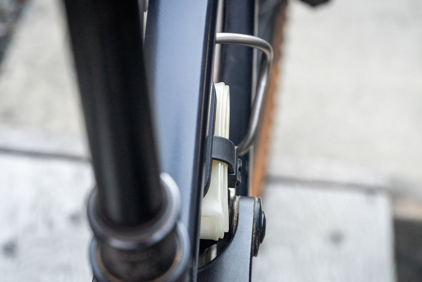 Image: The Standby Tube Strap Bracket, a clever bike accessory that conceals an Apple AirTag within a discreet bracket used to carry a spare tube on your bike. This lightweight and durable bracket is designed to blend in seamlessly and does not resemble a typical AirTag holder. It is specifically designed for use with Aerothan and Tubolito tubes and comes complete with a Voile Nano strap for easy installation. Made in Canada. top down.