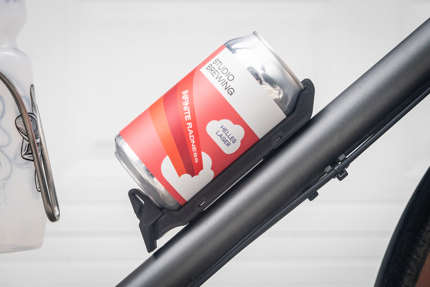 Image: The Canclaw, a lightweight and low-profile bike drink holder designed for standard 12oz (355ml) cans and 16oz (473ml) tall cans. It securely grips your beverage and can be attached using standard bottle cage bolt spacing or zipties. This product is 3D printed to order from ultra-strong carbon fiber nylon material and proudly made in Canada. Side Closeup.