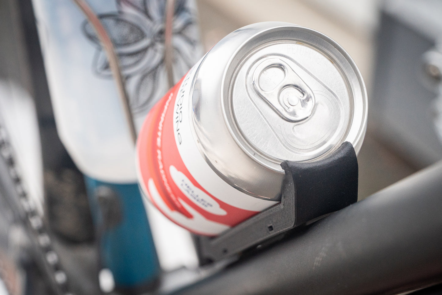 Image: The Canclaw, a lightweight and low-profile bike drink holder designed for standard 12oz (355ml) cans and 16oz (473ml) tall cans. It securely grips your beverage and can be attached using standard bottle cage bolt spacing or zipties. This product is 3D printed to order from ultra-strong carbon fiber nylon material and proudly made in Canada. Front Closeup.