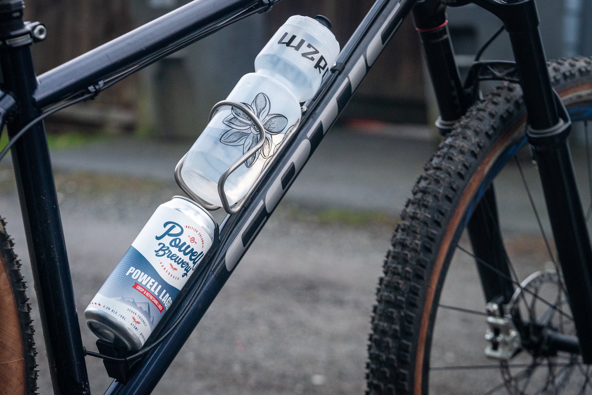 Image: The Canclaw, a lightweight and low-profile bike drink holder designed for standard 12oz (355ml) cans and 16oz (473ml) tall cans. It securely grips your beverage and can be attached using standard bottle cage bolt spacing or zipties. This product is 3D printed to order from ultra-strong carbon fiber nylon material and proudly made in Canada. Back Angle.